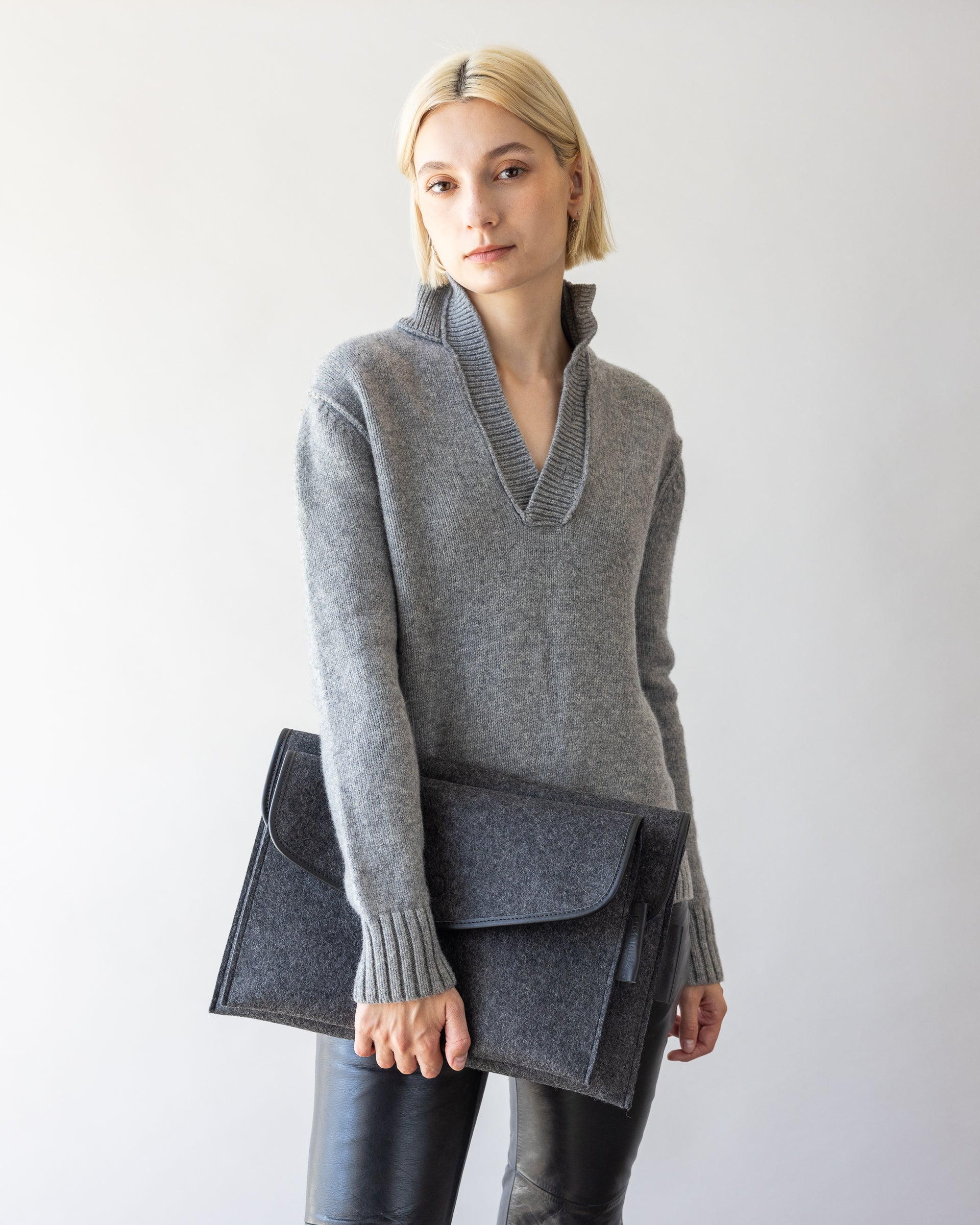 Envelope Merino Wool 14" and 16" Tech Sleeves both in charcoal held by a stylish woman in one hand by her side
