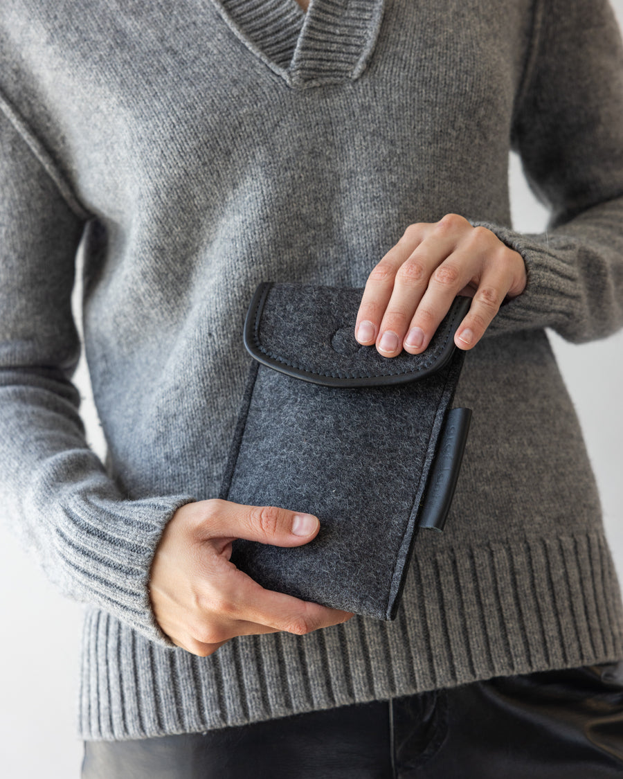 Merino Wool Envelope Accessory Sleeve in charcoal held by a woman in both hands, front view