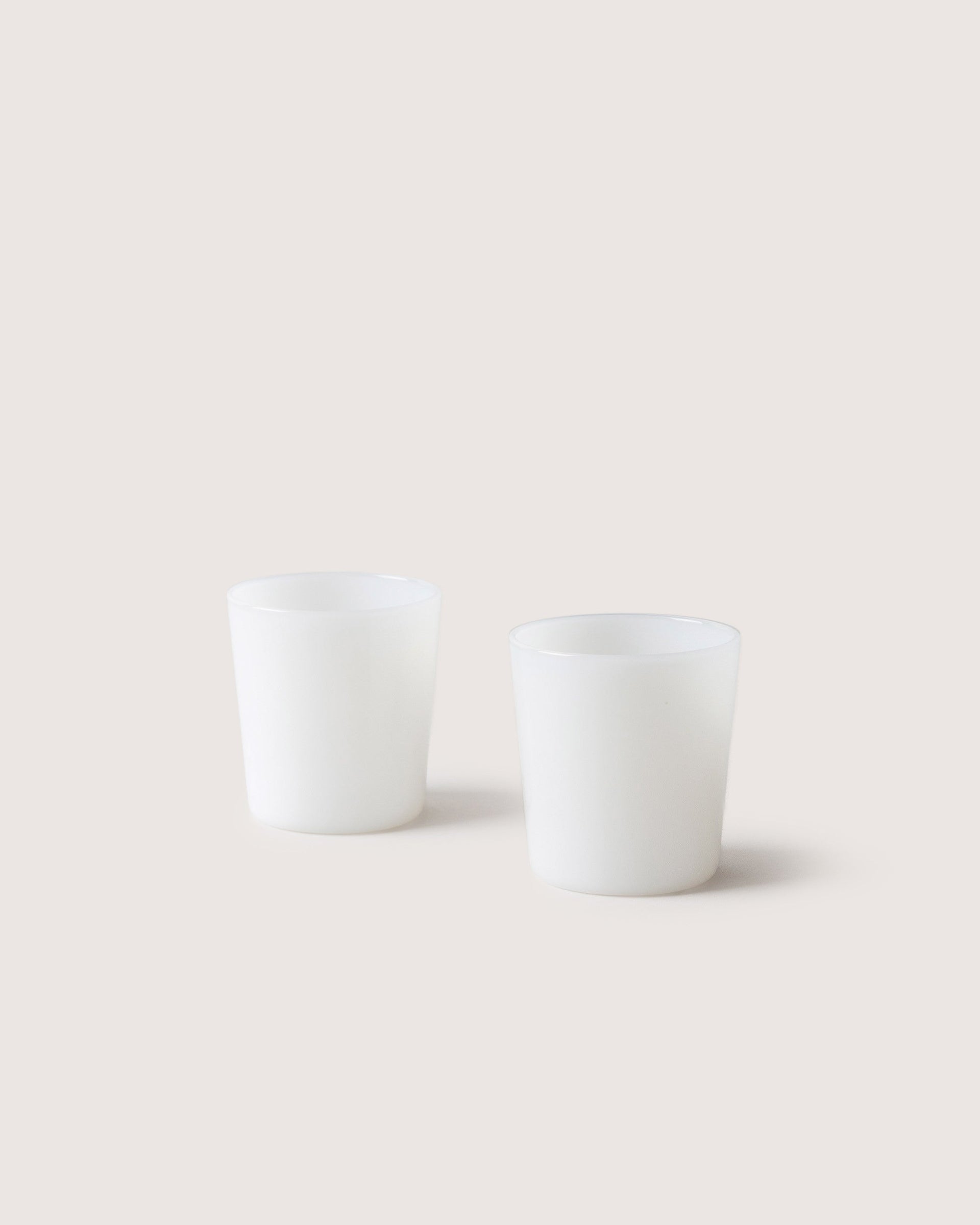 Two small Glas Tumbler in color foam, white background