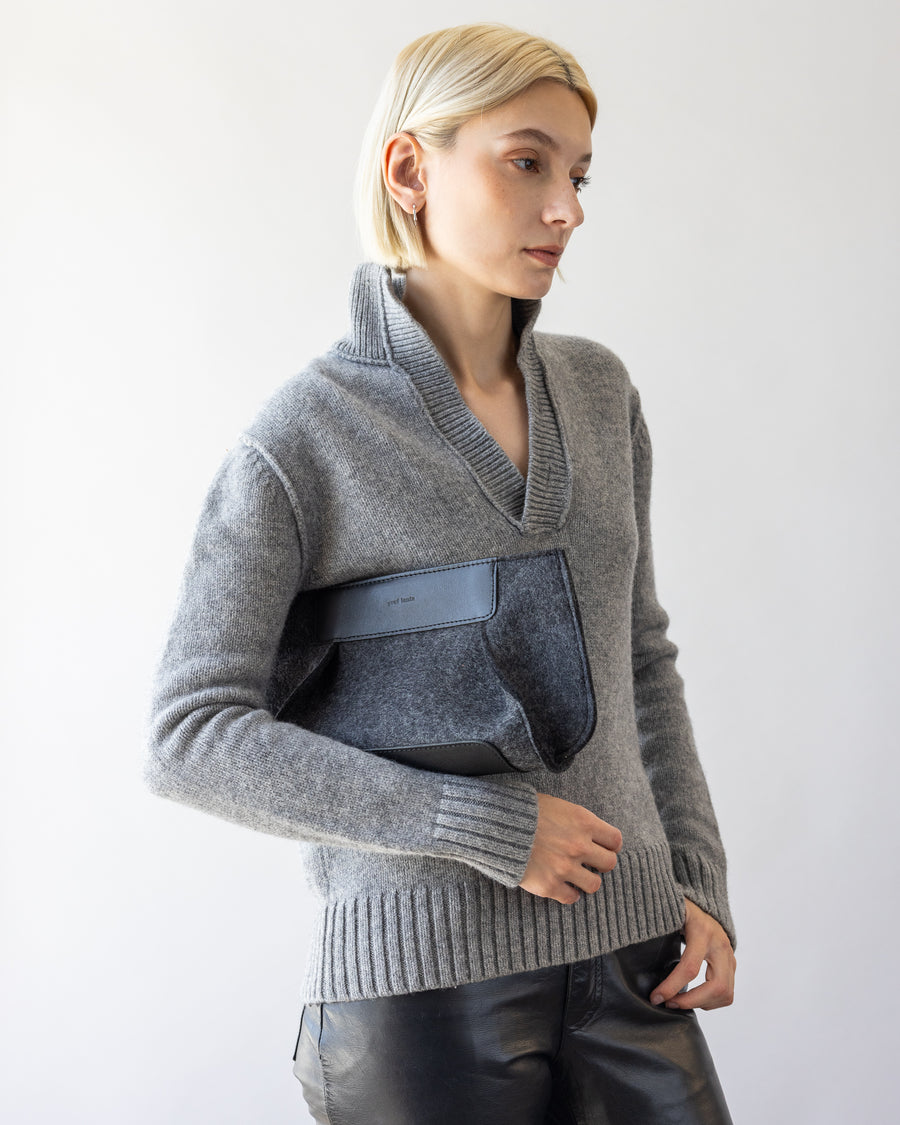 A dark gray Frankie Merino Wool Clutch casually held by a woman under her arm  