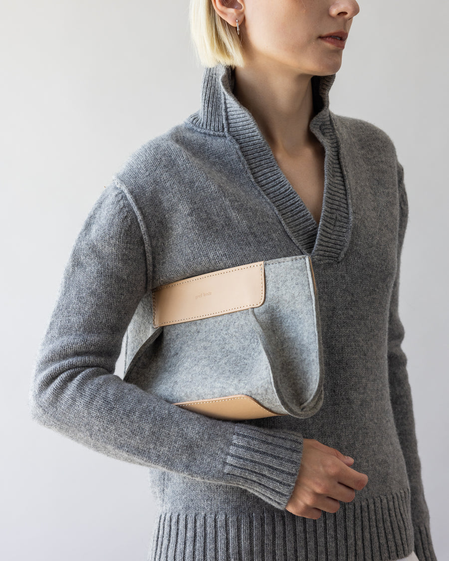 A gray Frankie Merino Wool Clutch casually held by a woman under her arm  