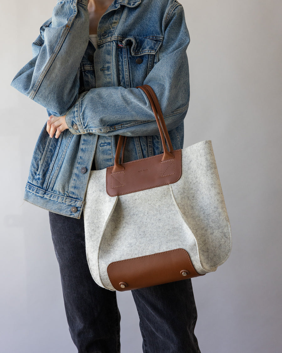 Frankie Midi tote bag in white with brown leather handle and applications held by woman over one arm,