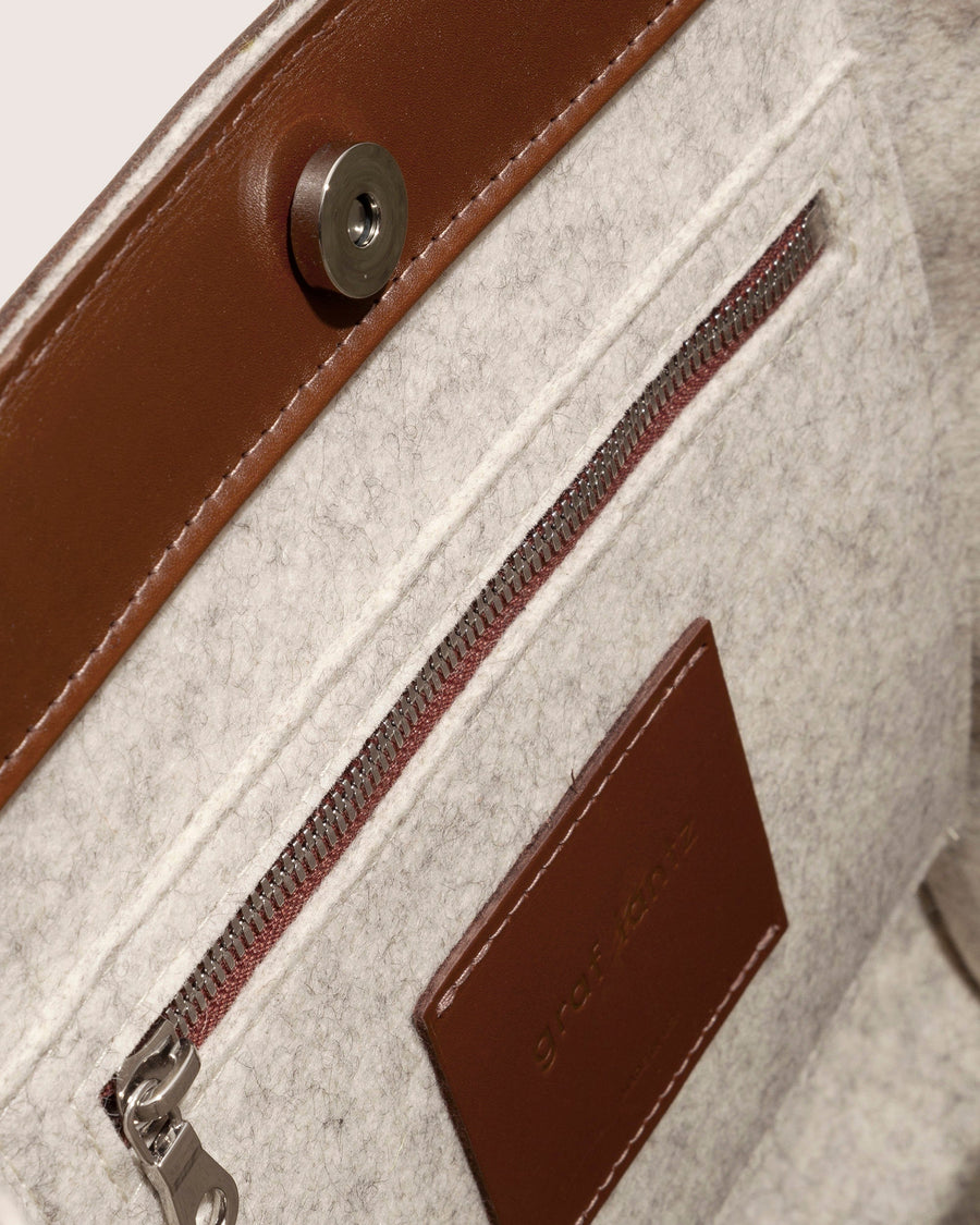 View inside white Frankie Merino Wool Tote featuring pocket, zipper, and brown leather applications.