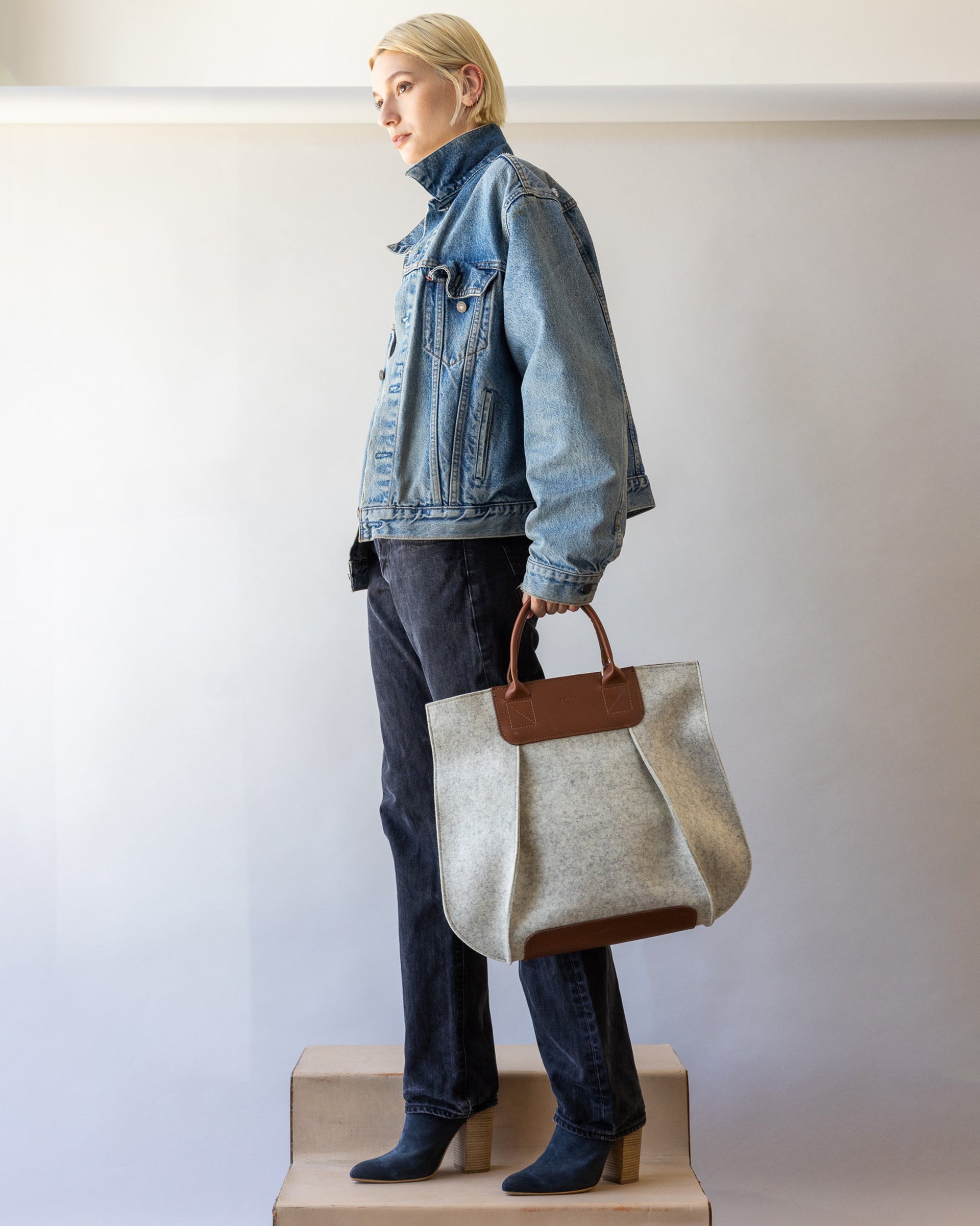 Standing woman with white and brown colored Frankie Merino Wool Tote by Graf Lantz in one hand by her side.