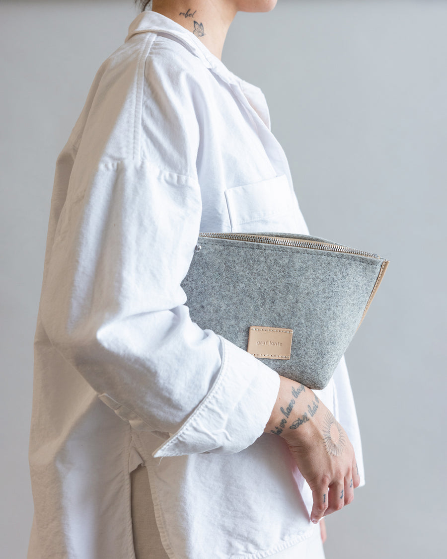 Standing woman with gray Granite Hana Merino Wool Pouch Bag under her arm