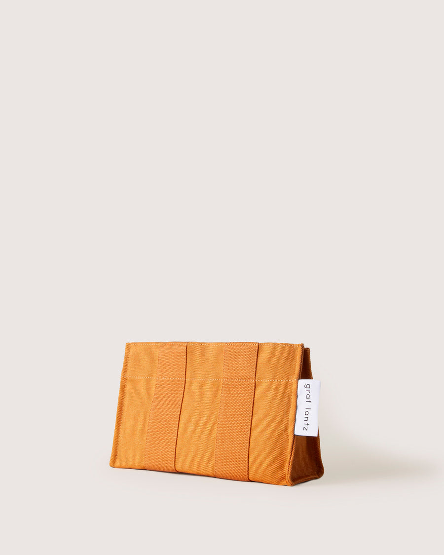 When the sun goes down it does double duty as a casual but elegant clutch: our Hako Pouch. Here in caramel color.