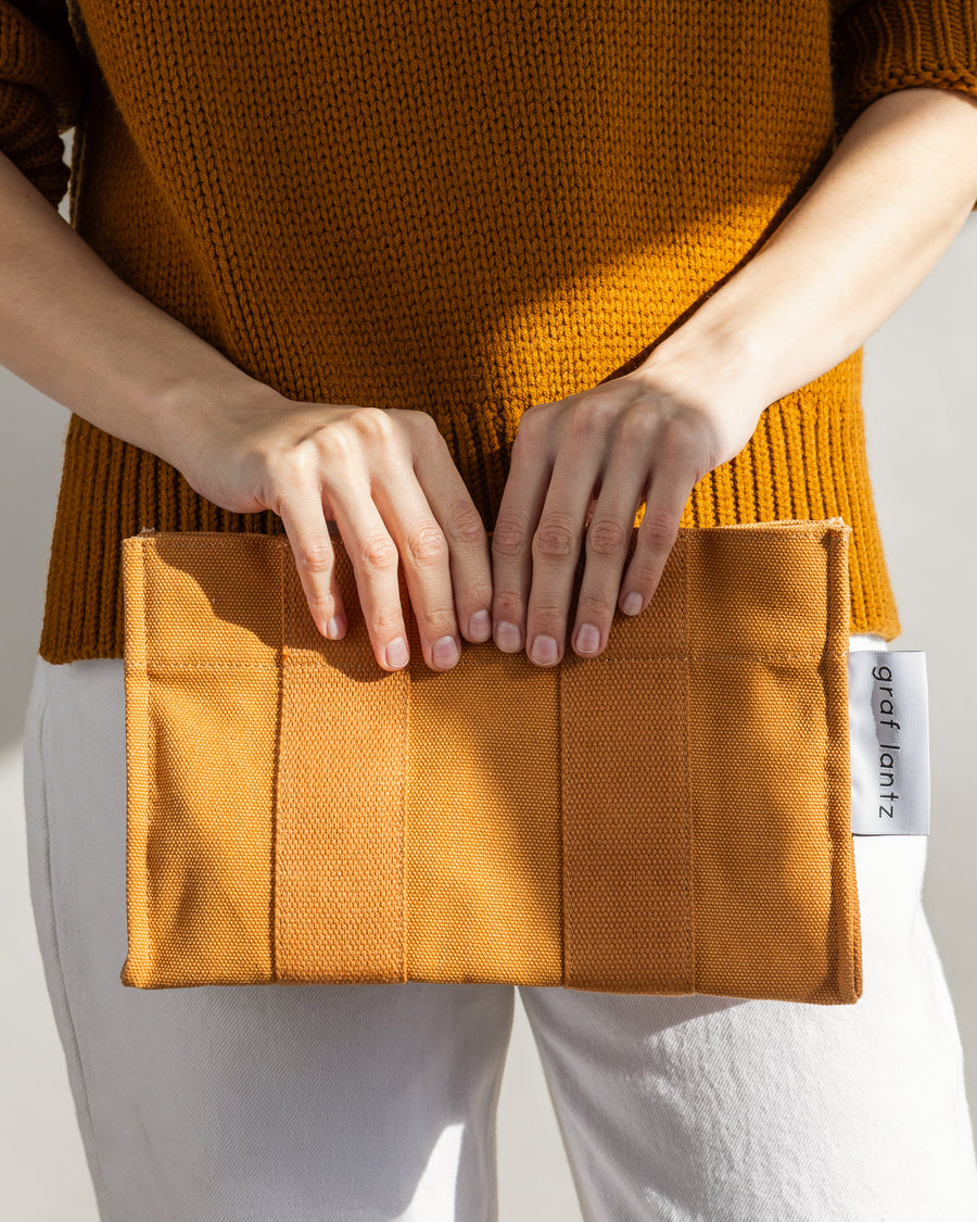 When the sun goes down it does double duty as a casual but elegant clutch: our Hako Pouch. Here in caramel color.