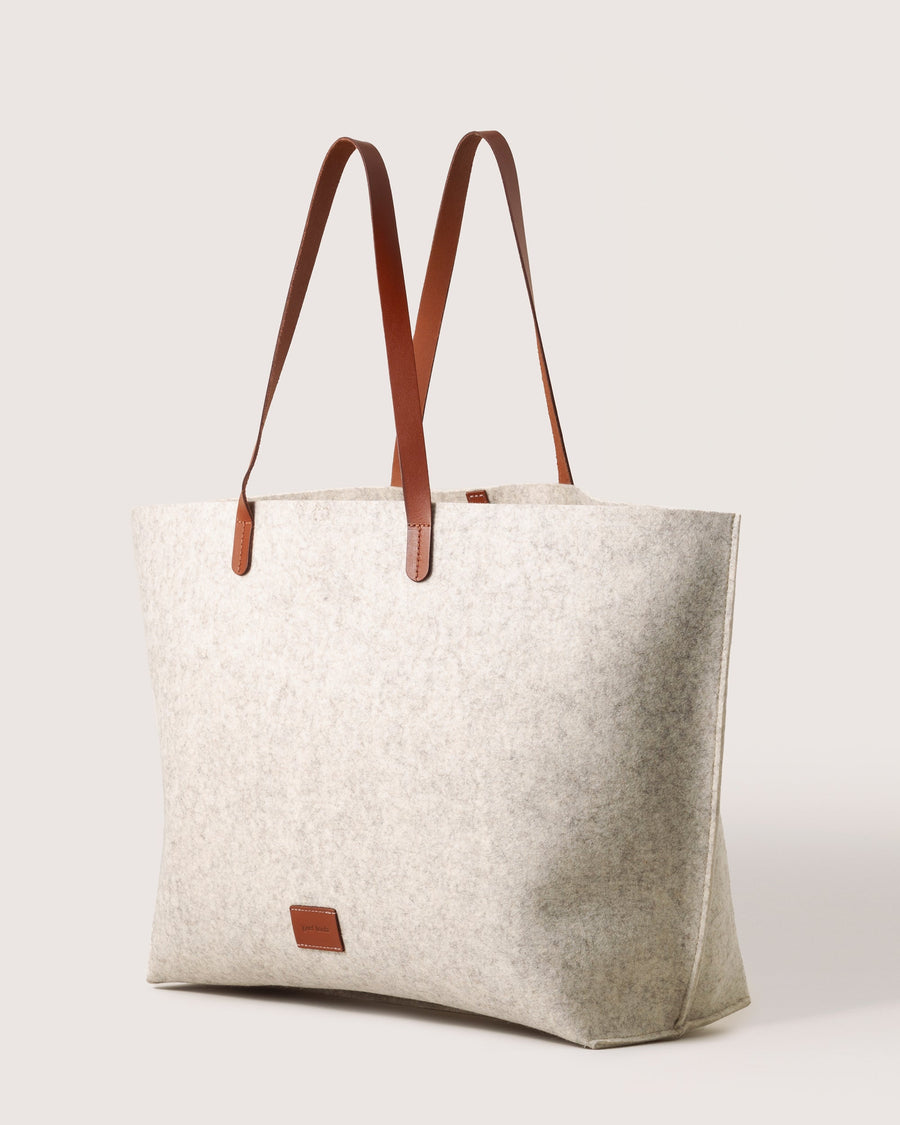 White Hana Merino Wool Boat Bag by Graf Lantz with brown leather handles and brand logo, side view, white background.