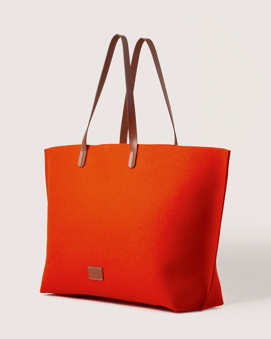 Orange Hana Merino Wool Boat Bag by Graf Lantz with brown leather handles and brand logo, side view, white background.