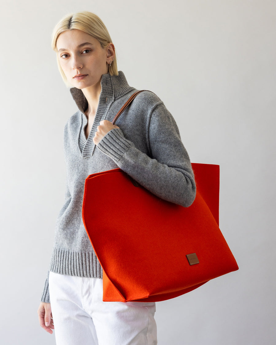 Standing woman with orange Hana Merino Wool Boat Bag over her shoulder, front view