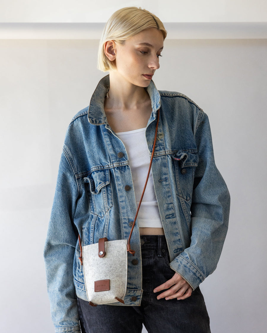 White Hana Merino Wool Phone Crossbody diagonally across a woman's body, with the strap over one shoulder and the bag resting on the opposite hip.