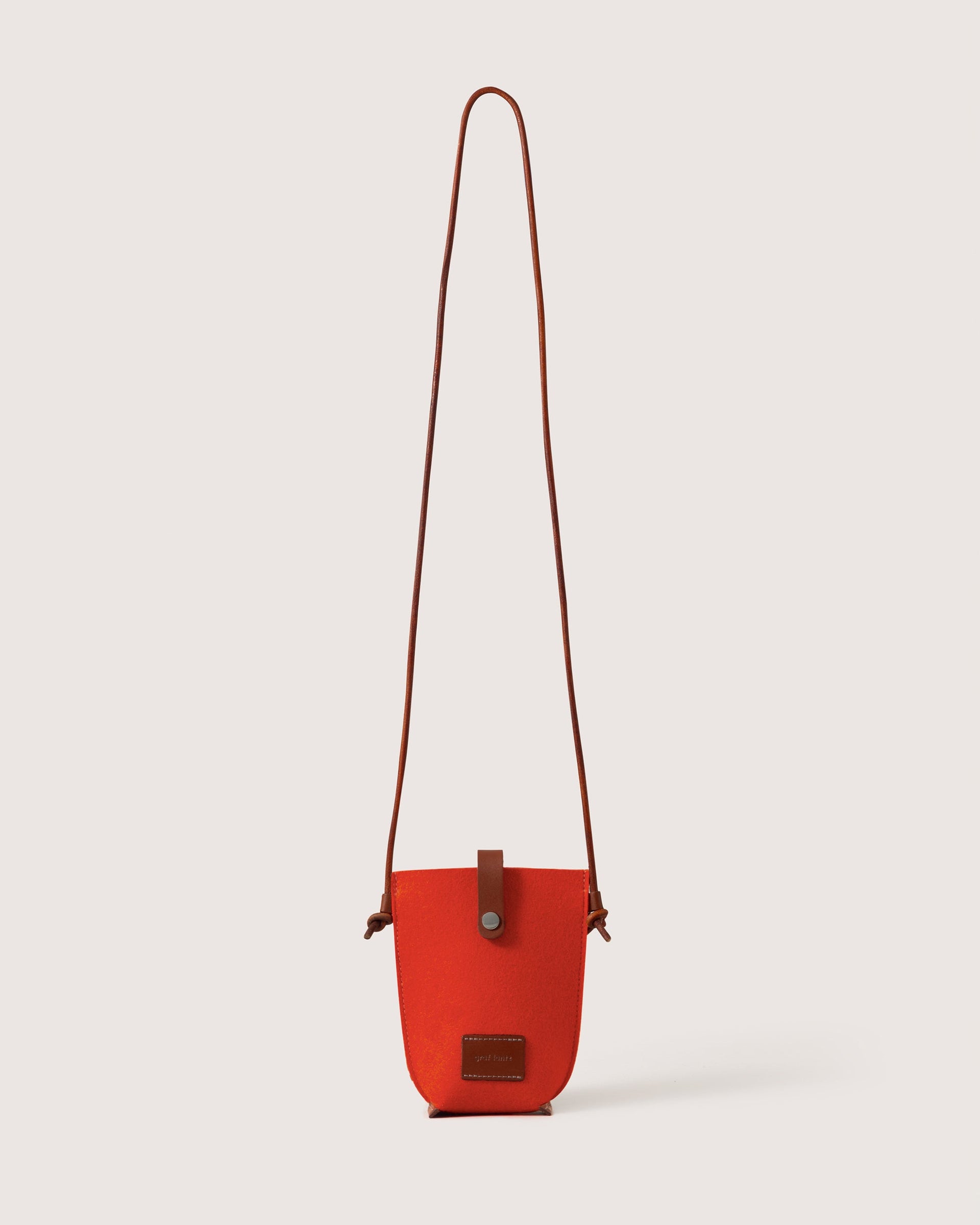 Orange Merino Wool Phone Crossbody with dark brown leather strap, brand label, and snap closure, white background.