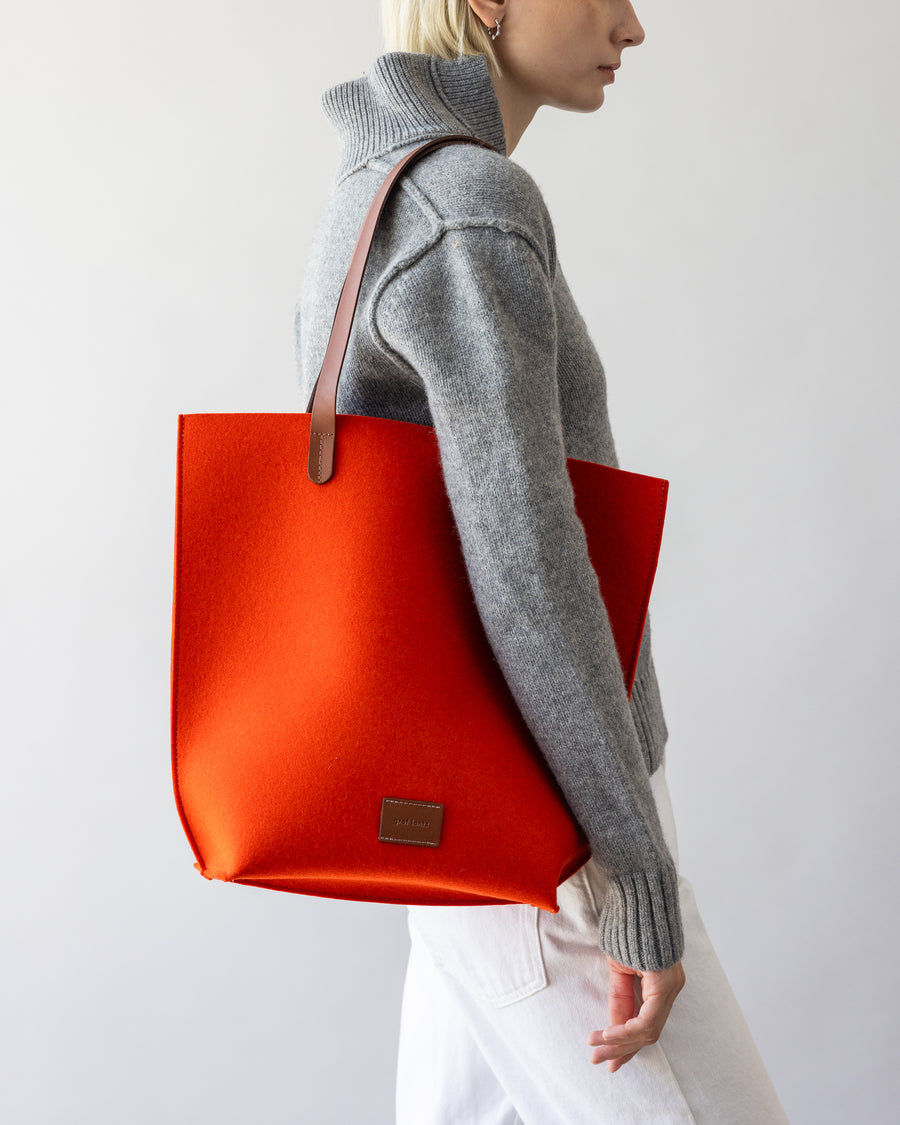 Orange Merino Wool Tote bag with brown leather handle on a woman's shoulder, side view