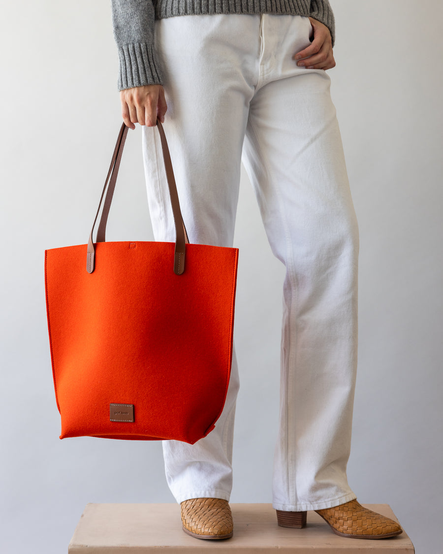 Orange Merino Wool Tote bag with brown leather handle held by a woman's hand