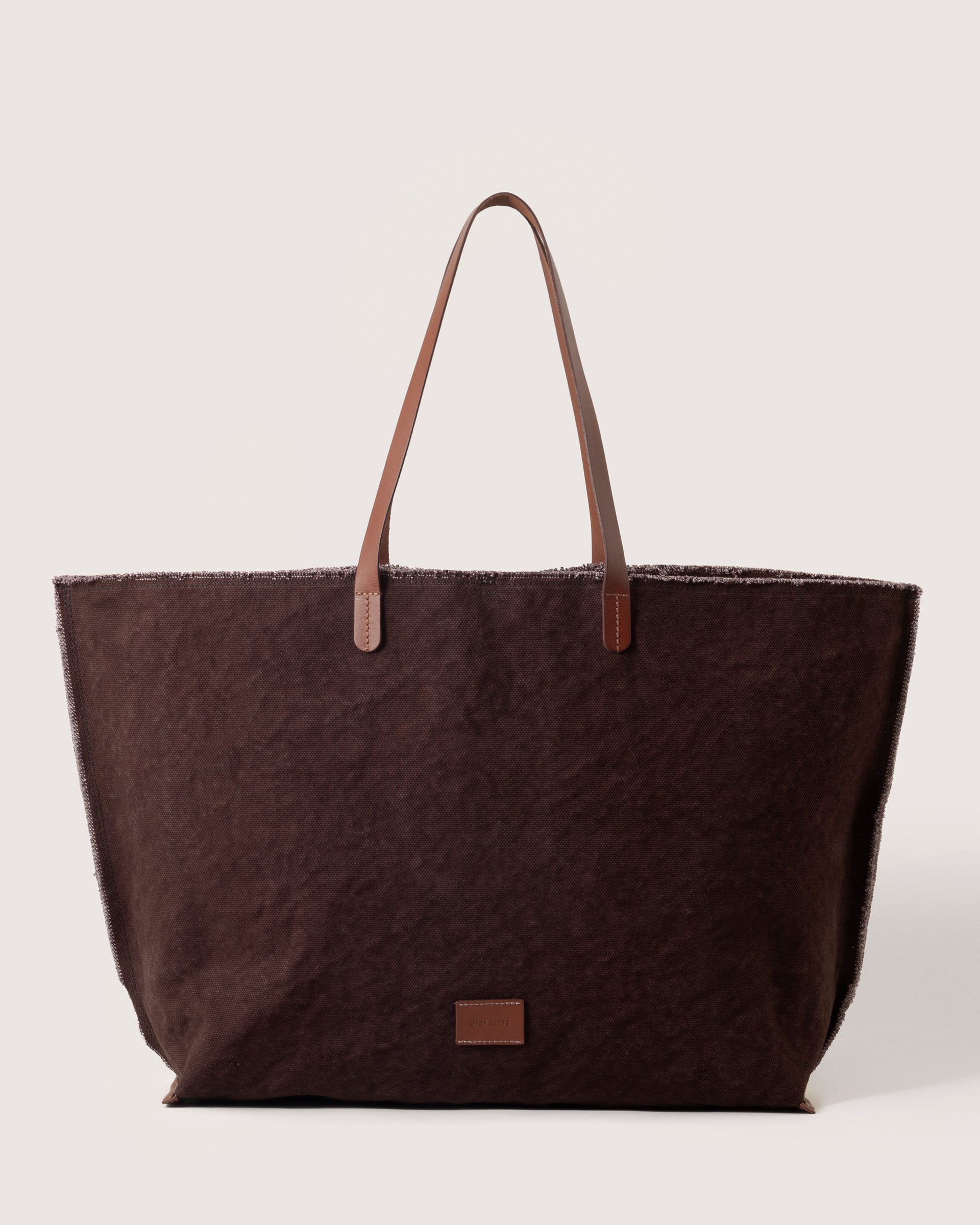 A Hana Canvas Boat Bag in Deep Brown Sienna with dark brown leather handle, white background