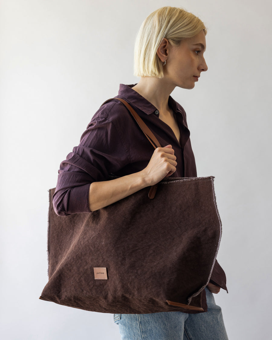 A blonde woman carrying a brown Hana Canvas Boat Bag over her shoulder 