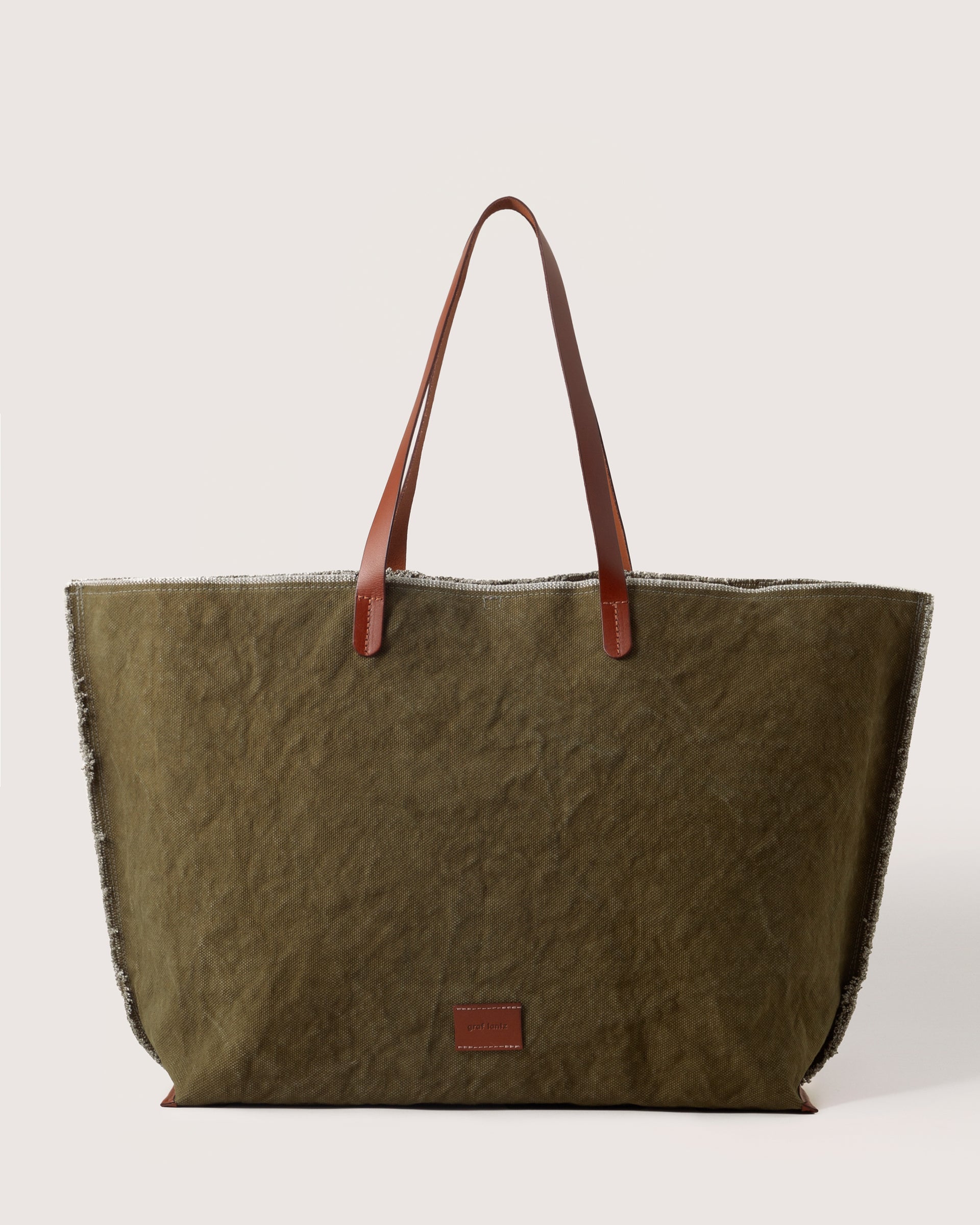 A Hana Canvas Boat Bag in Olive Sienna with dark brown leather handle, white background