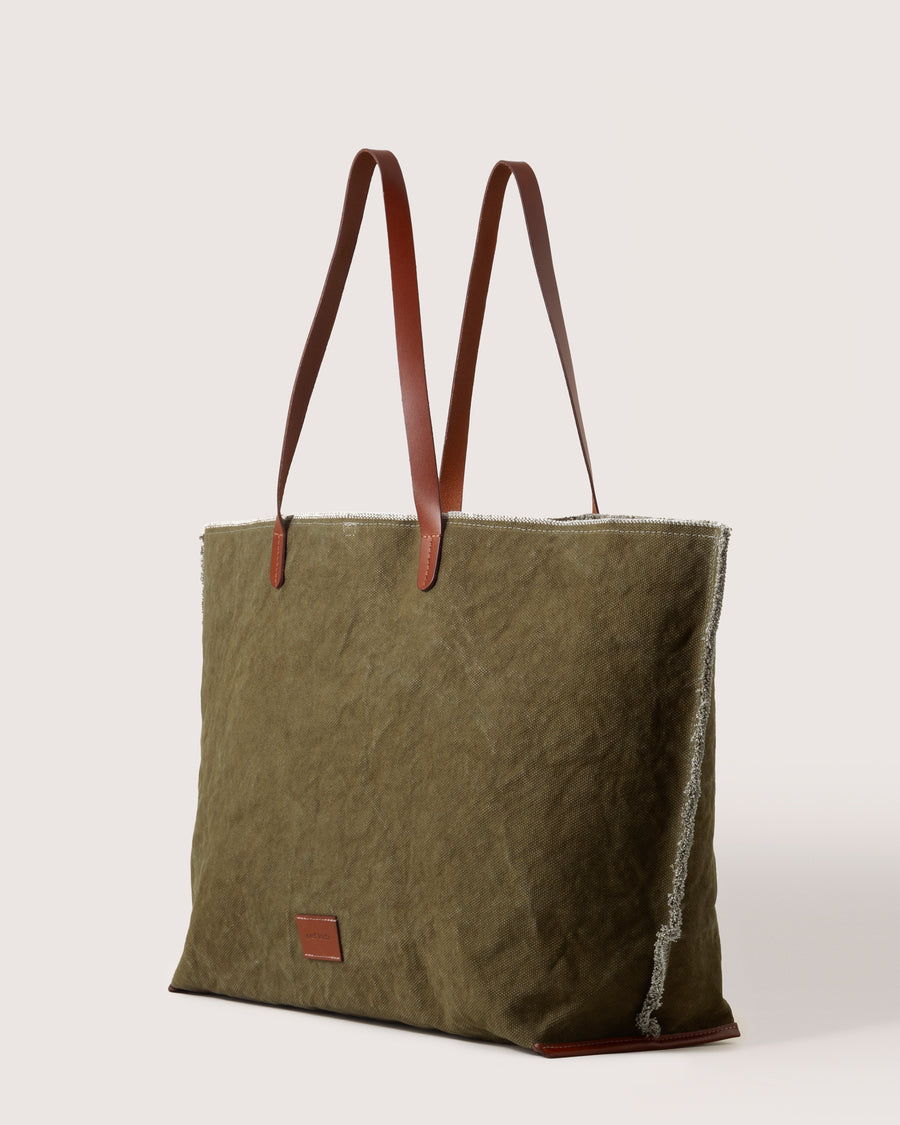 A dark green Hana Canvas Boat Bag with dark brown leather handle, white background, side view