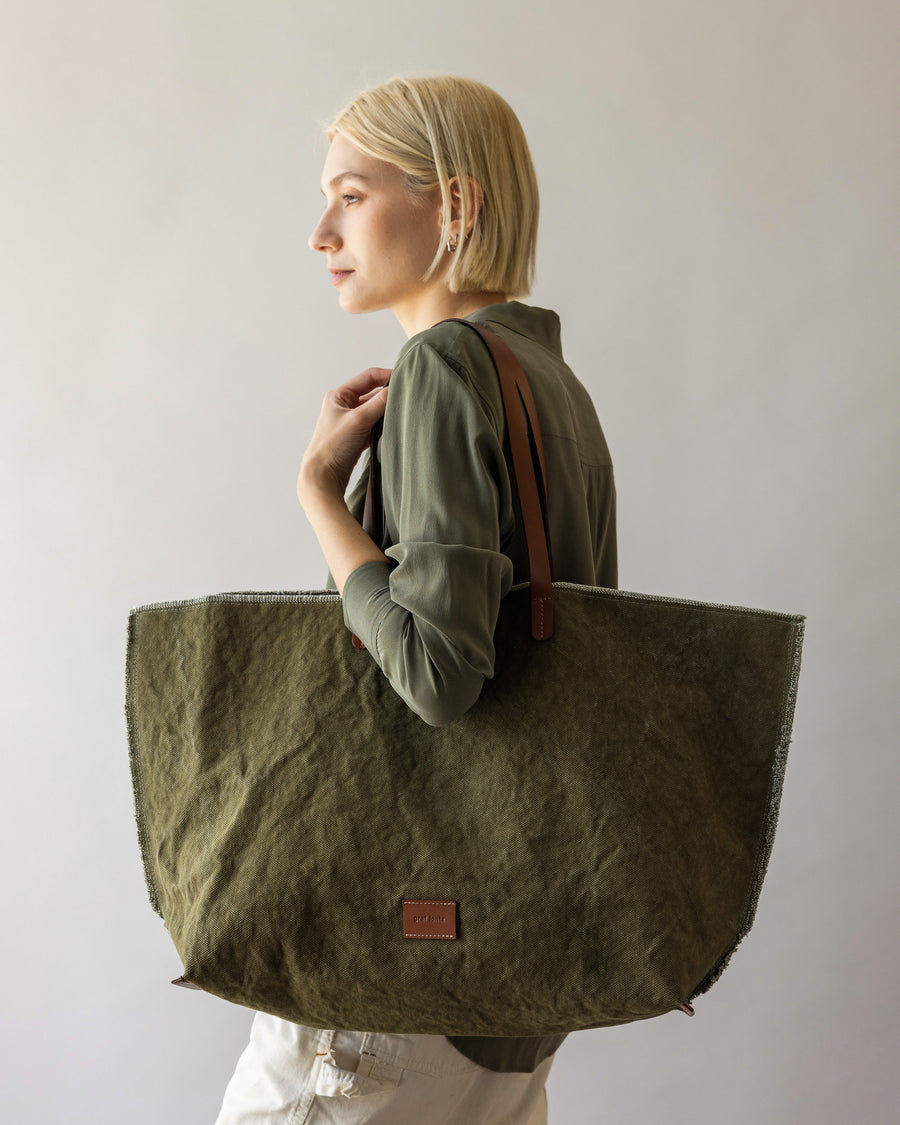 A blonde woman carrying a green Hana Canvas Boat Bag over her shoulder 