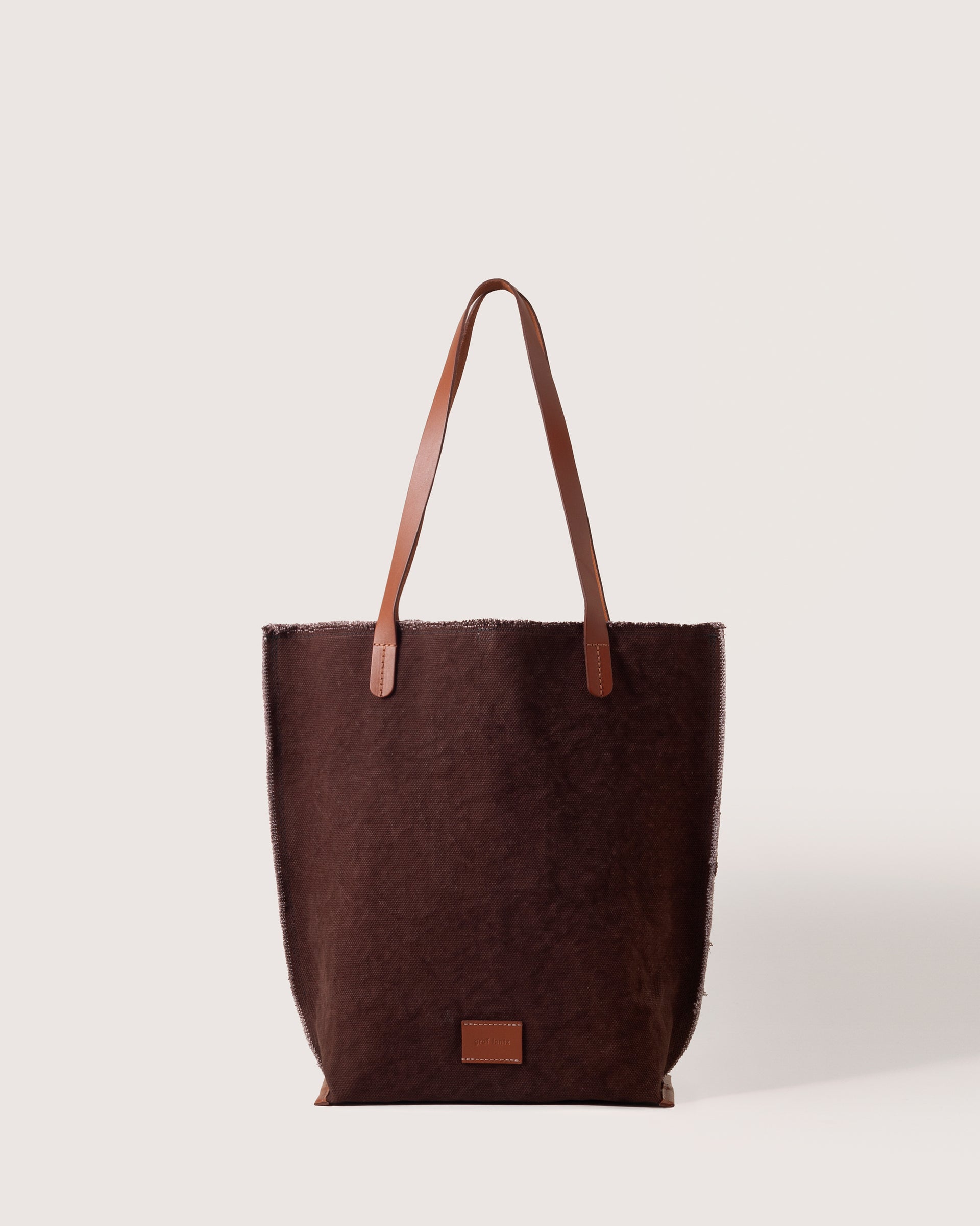 A Hana Canvas Tote in Deep Brown Sienna with dark brown leather handle, white background