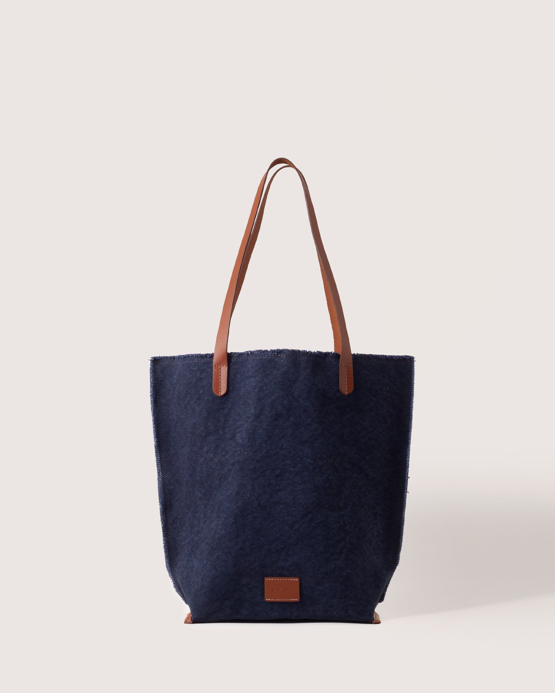 A Hana Canvas Tote in Midnight Sienna with dark brown leather handle, white background