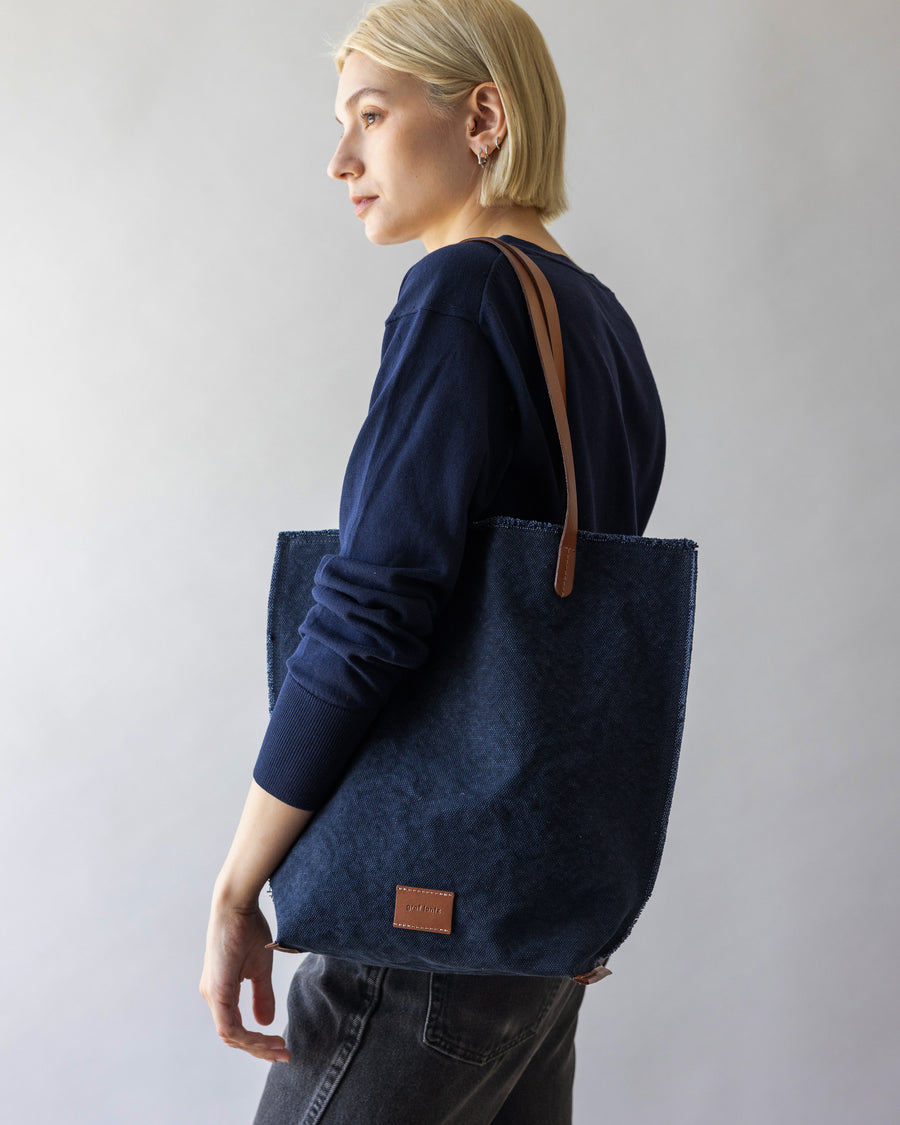 A blonde woman carrying a blue Hana Canvas Tote over her shoulder 
