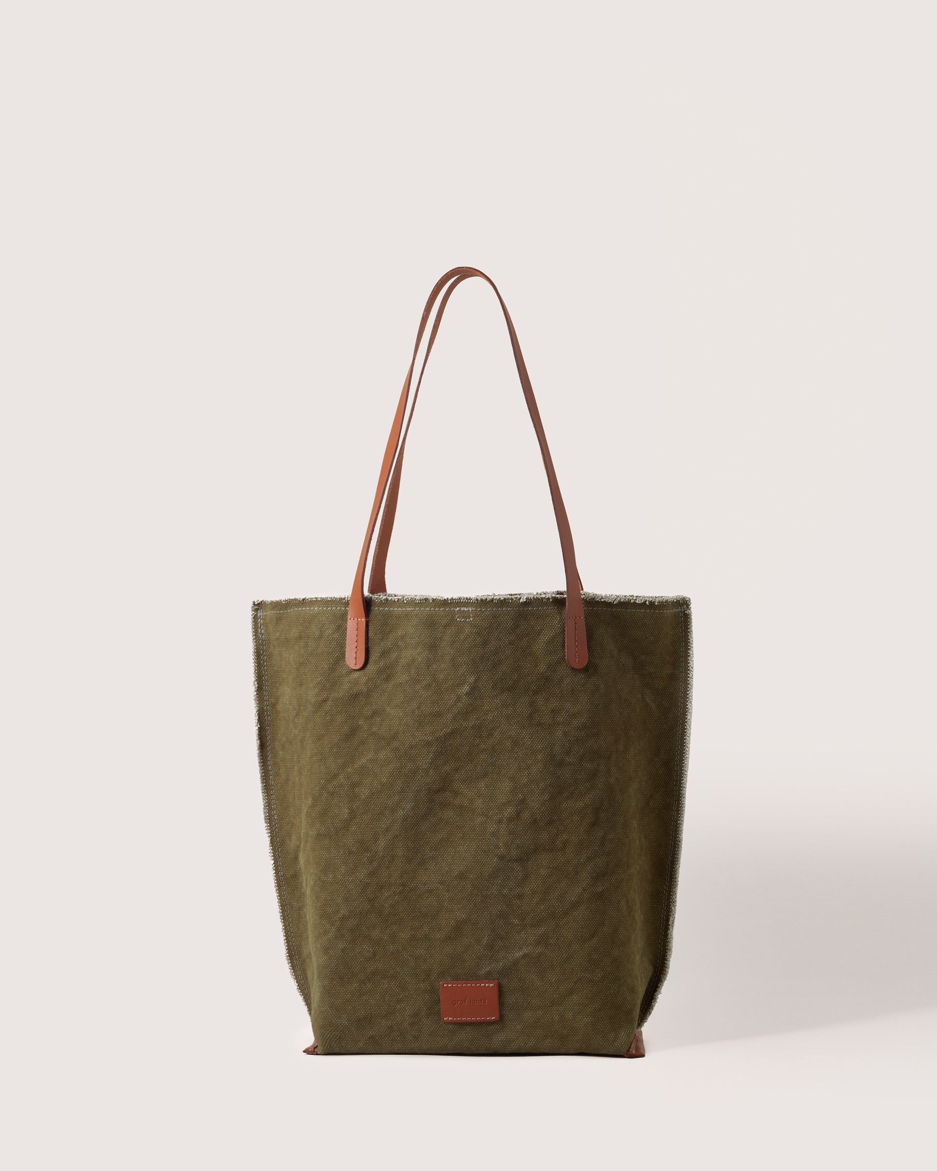 A Hana Canvas Tote in Olive Sienna with dark brown leather handle, white background