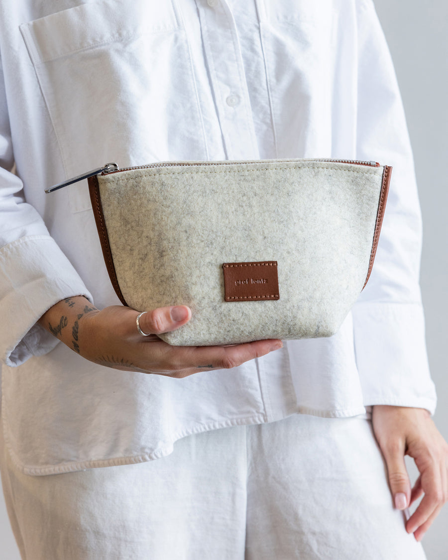 Standing woman holds White Hana Merino Wool Pouch in one hand in front of her