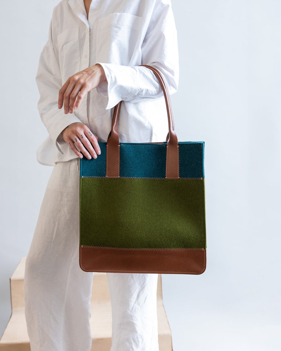 Woman with a Jaunt Merino Wool Tote in Moss and Kombu over her arm, side view