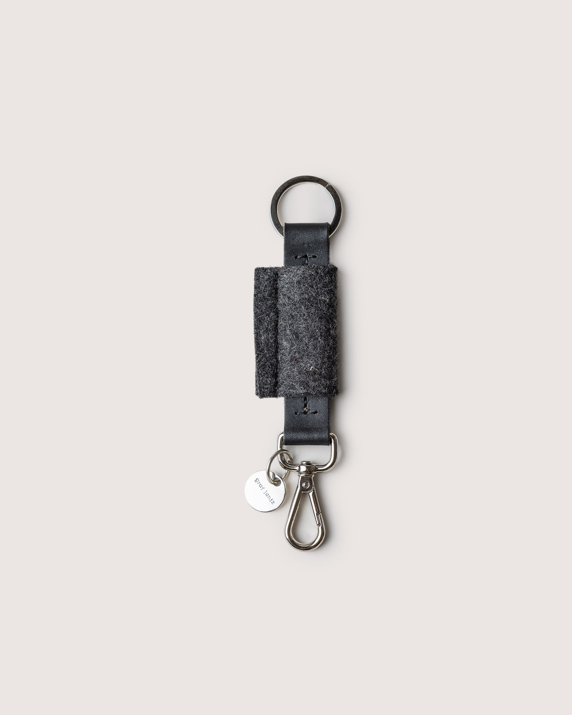 Merino Wool Bar Key Fob in charcoal with silver colored key ring, lobster clasp, and brand logo, white background.