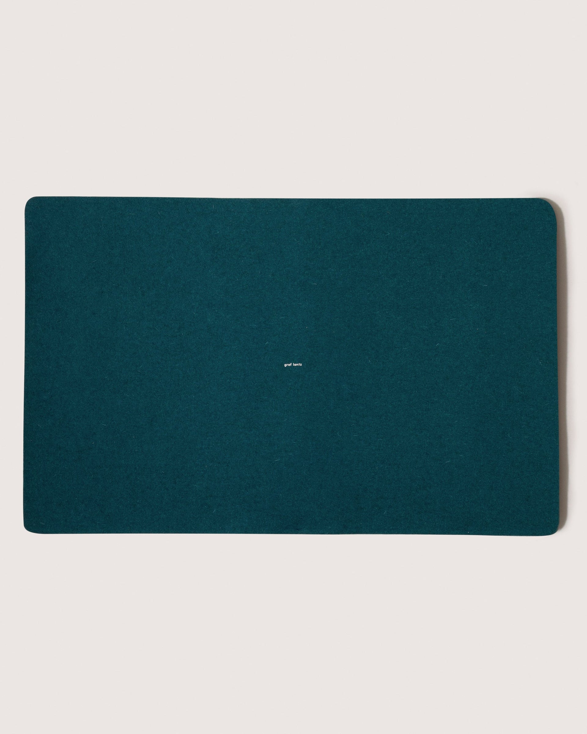 Mosen Merino Wool Large Desk Pad in Kombu-green color with small white brand logo in the middle, white background