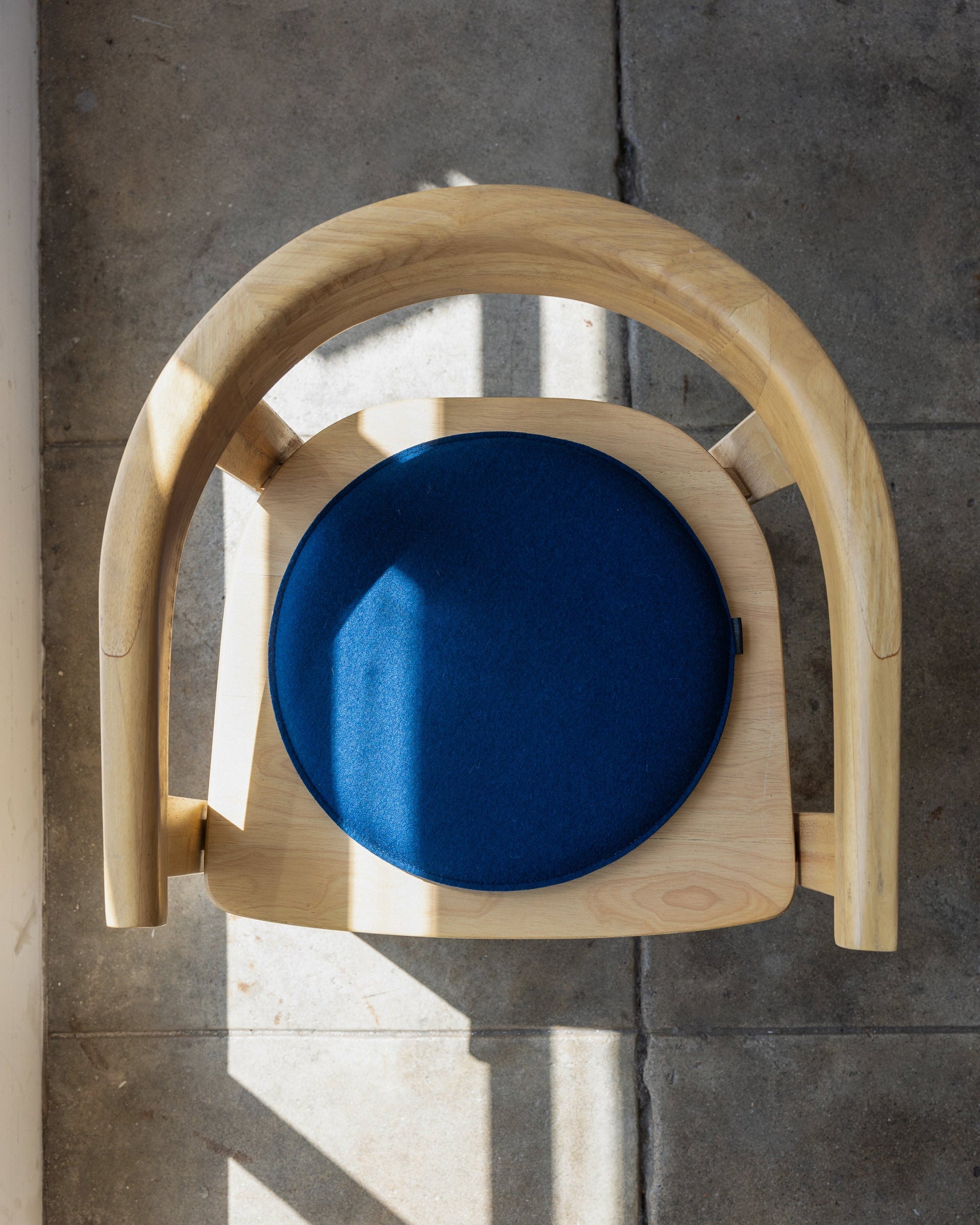 Blue Zabuton Merino Wool Round Seat Pad i\on a wooden chair, view from above