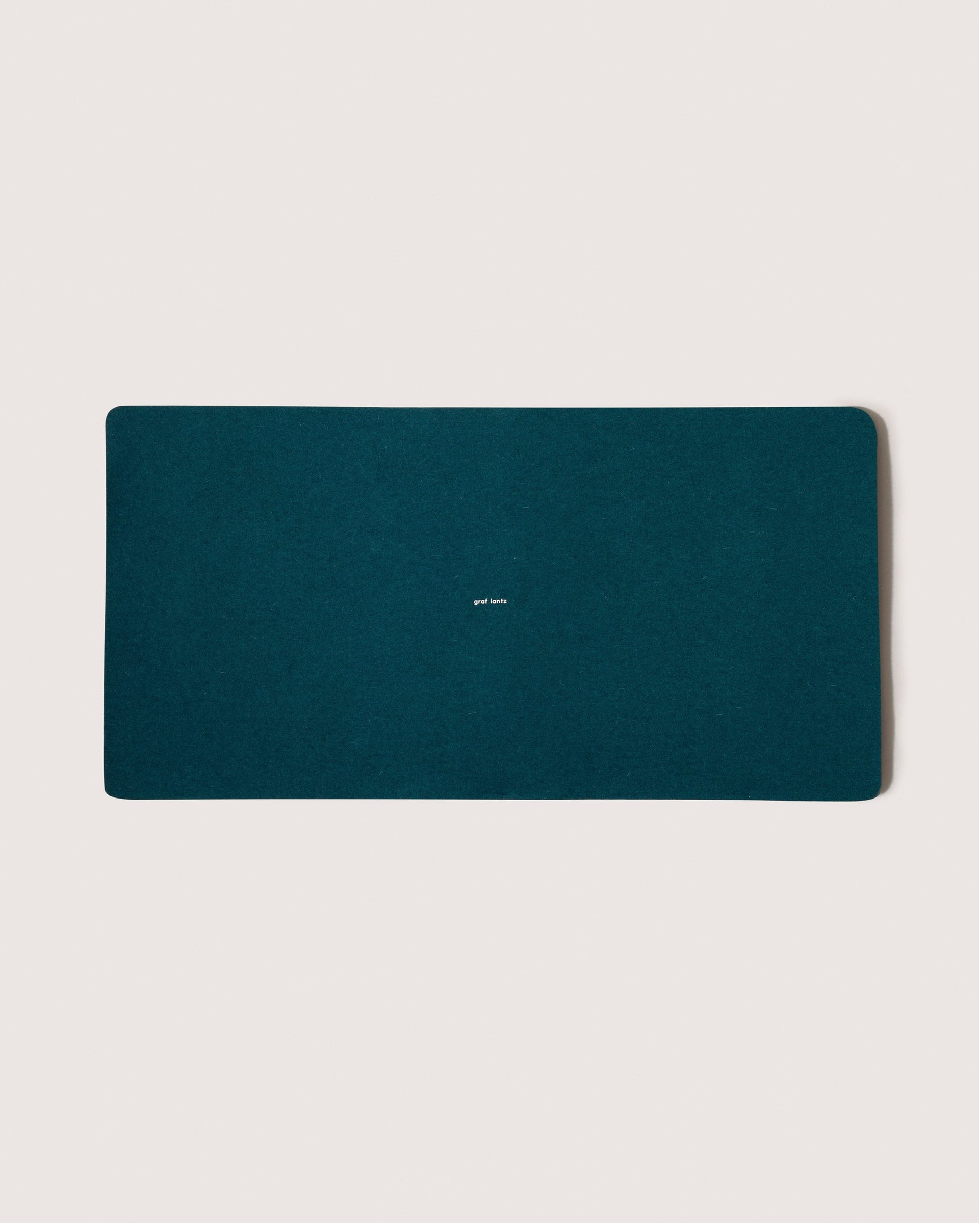 Mosen Merino Wool Medium Desk Pad in Kombu-green color with white brand logo in the middle, white background