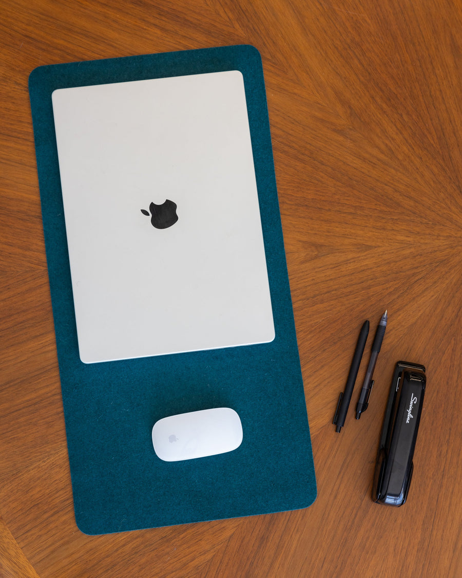 White laptop and mouse on Kombu Mosen Merino Wool Medium Desk Pad on a wooden tabletop