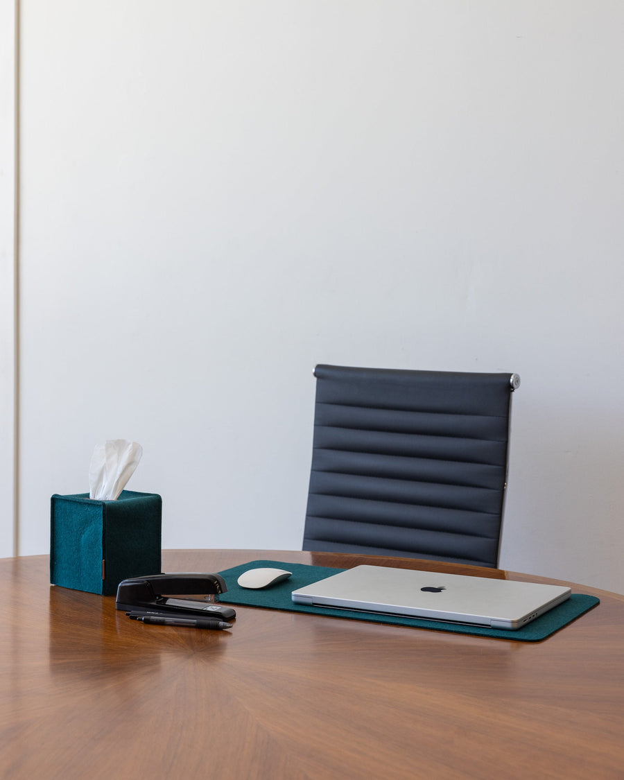 Office scene with office chair and wooden desk, on tabletop a Kombu Mosen Merino Wool Medium Desk Pad with white laptop and mouse next to a color-matching Kombu Merino Wool Small Tissue Box Cover