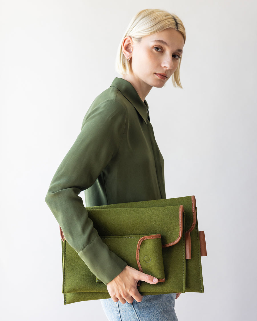 Envelope Merino Wool 14" and 16" Tech Sleeves and Envelope Accessory Sleeve in green held by a stylish woman in one hand by her side