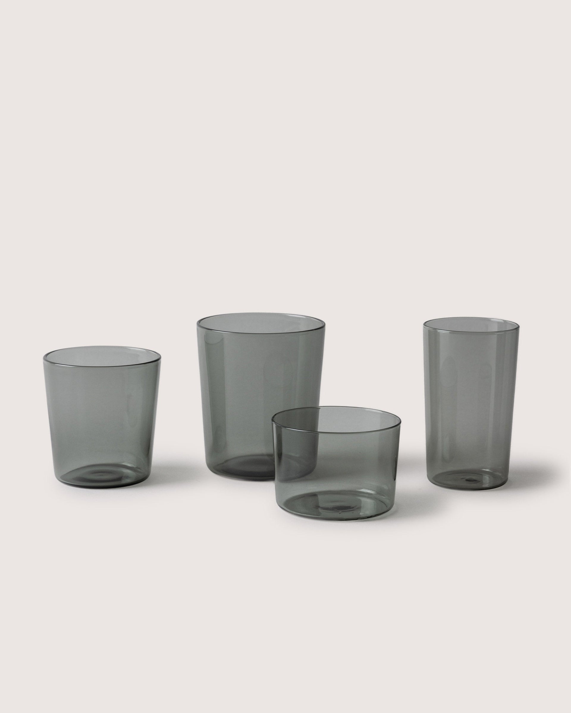 Selection of drinking glasses and a small bowl in color smoke by Graf Lantz, white background