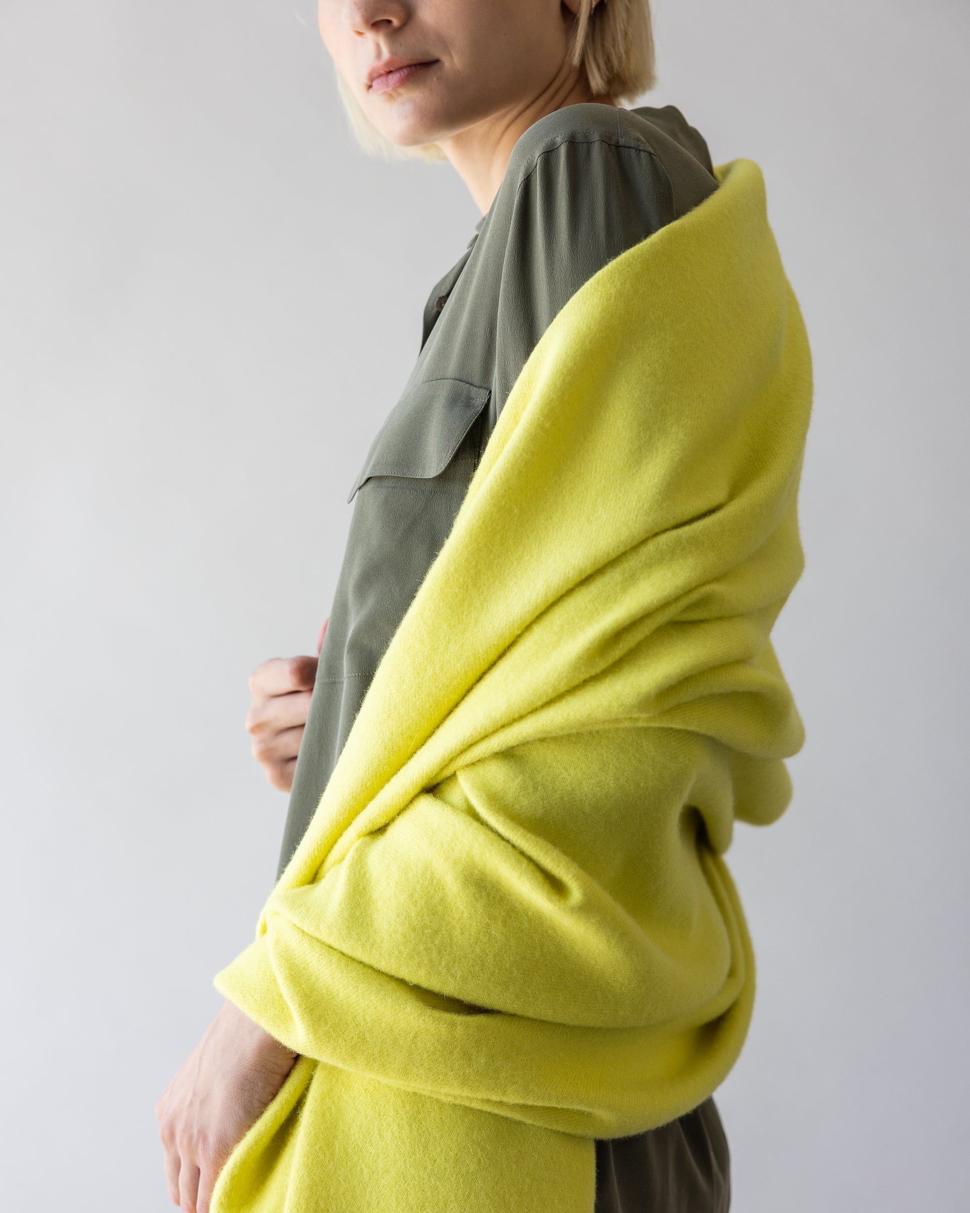 Blonde woman with a citron-colored alpaca throw by Graf Lantz over her right shoulder, side view